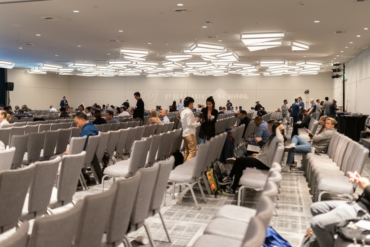 Adulti diversi che fanno rete e partecipano a una conferenza in una sala moderna.