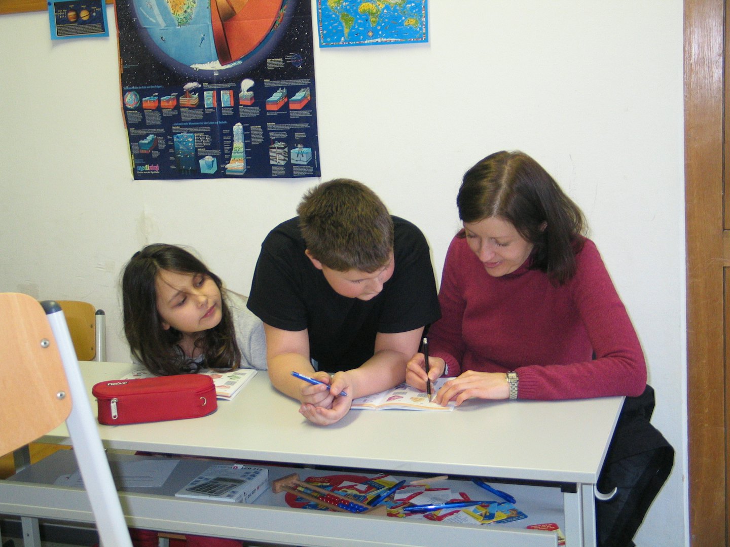 Un insegnante aiuta due bambini con un'attività a una scrivania.