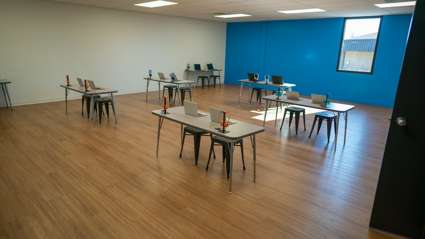 Sala riunioni moderna con laptop e cuffie sui tavoli.